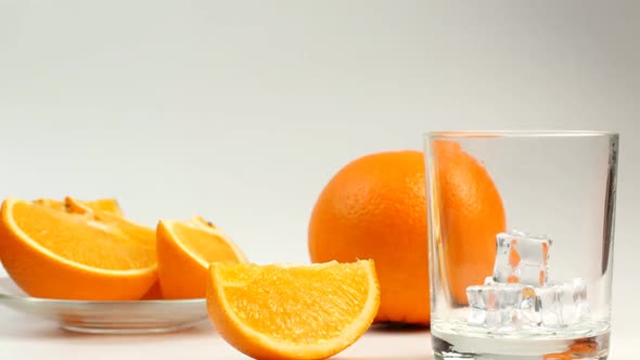 Orange Juice And Slices Of Orange Are Poured Into A Glass On A Plate On A White Background
