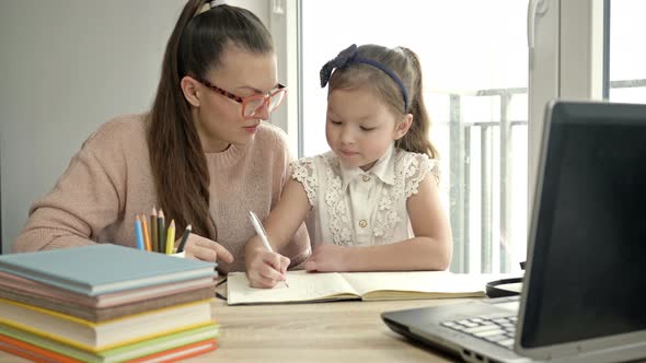 Young Woman Is Helping Her Little Daughter with Homework. Back To School. alt