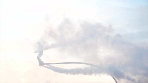 Unrecognizable Man on Flyboard is Making Tricks with Smoke Bomb