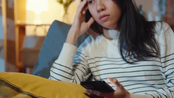 Asia lady holding phone feeling sad waiting for call sit at sofa in living room at house night.