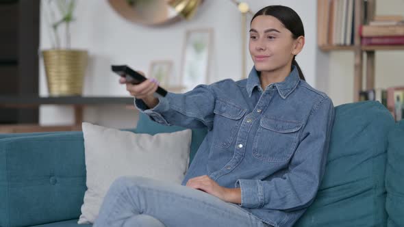 Latin Woman Watching Television at Home  alt