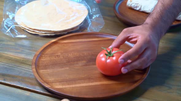 Men's Hands Beautifully Spread Tomatoes on a Wooden Round Cutting Board alt