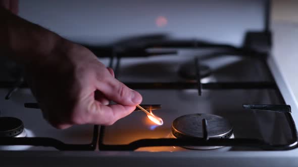 A man lights a gas stove with a match alt