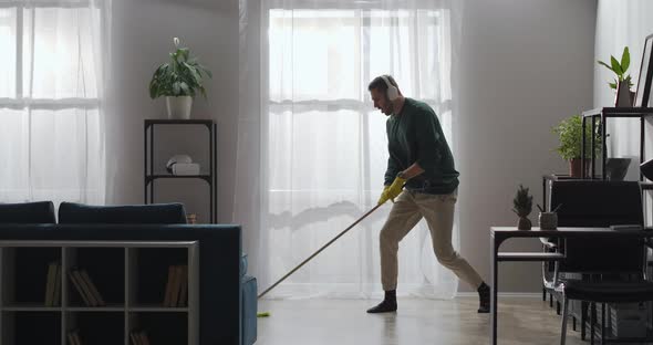 Cheerful Man Is Having Fun During Home Cleanup Washing Floor and Dancing with Mop Singing and alt