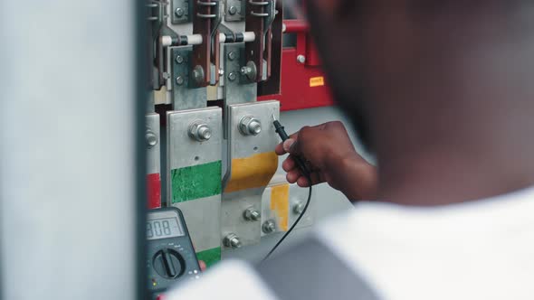 Close Up of African American Man Standing Near Switchgear Compartment with alt