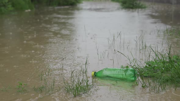 An Empty Plastic Bottle of Carbonated Drinks Floats on the Water During a Flood. Very Dirty Water