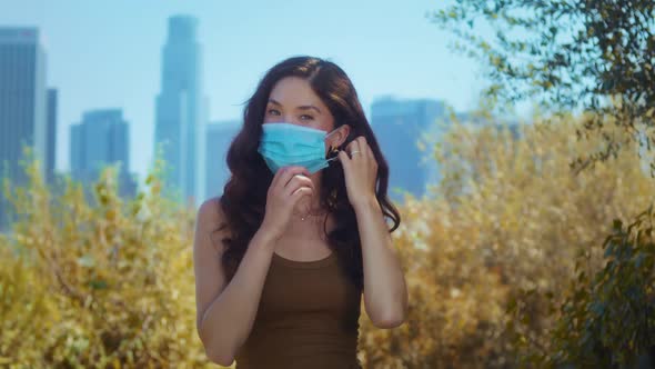 Brunette Taking Off Face Mask in Park alt