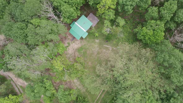 Aerial view of mountain hillside with small hut in the forest alt
