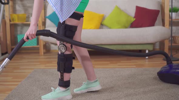 Female Housewife After Injury Knee Bend Orthosis Knee Brace Vacuums in the Living Room alt