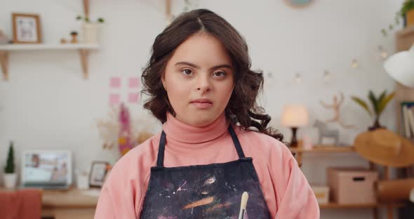 Close Up of Adorable Teen with Down Syndrome Wearing in Artists Apron and Holding Paintbrush alt