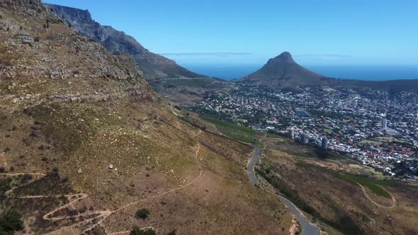 Drone shot of Cape Town - drone is reversing near Woodstock Cave at Table Mountain, facing Lions Hea alt