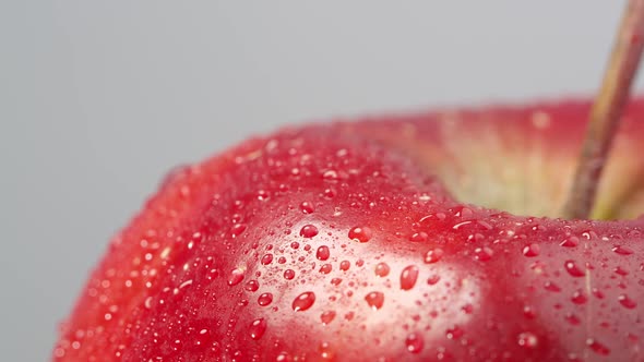 Close up of a red apple spinning with water on it alt