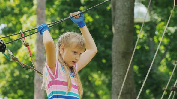 The Girl Walks on the Ropes High Above the Ground Uses a Safety Rope alt