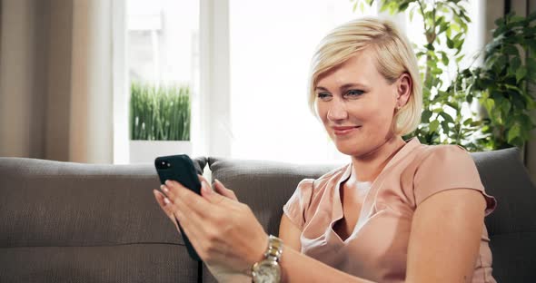 Woman with Smartphone Sitting on Sofa