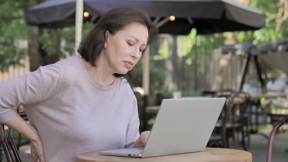 Old Woman with Back Pain Working on Laptop Outdoor alt