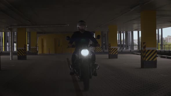 Man Riding Scrambler Motorbike Though Yellow Multilevel Parking alt