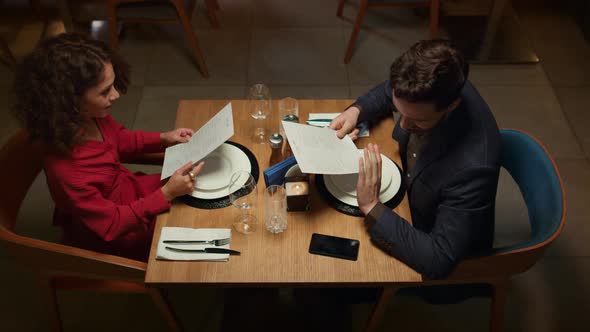 Attractive Couple Choosing Menu in Night Restaurant alt