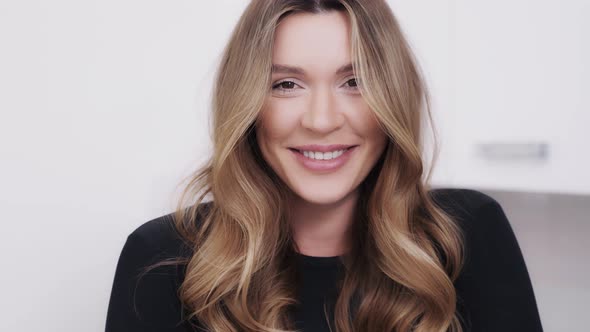 Alluring Dark Blonde Smiling and Touching Her Long Hair alt