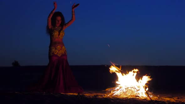 Brunette Dancing Belly Dance Near the Fire, Against a Beautiful Sunset alt
