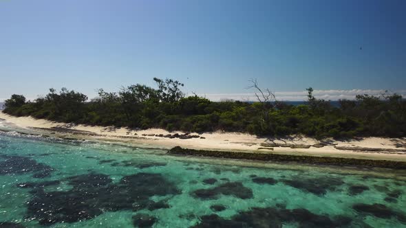 Flyover towards sailboat anchored off beautiful deserted tropical island, New Caledonia. alt