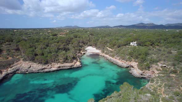 Flying over turquoise water towards the white sandy beach  of Cala Sa Nau alt