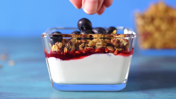 Adding blueberry to yogurt, granola and jam. Healthy breakfast alt