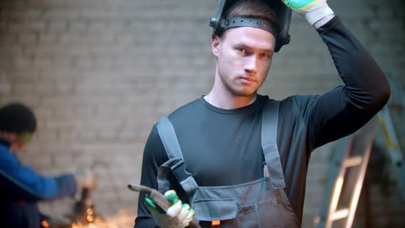 Young Handsome Man Walking in the Workshop Holding a Welding Instrument alt