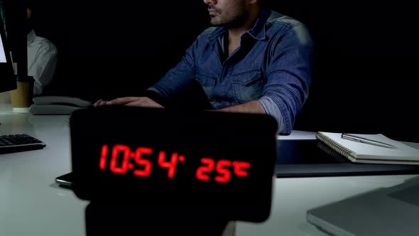 Workaholic man staying overtime late at night in the office working on computer