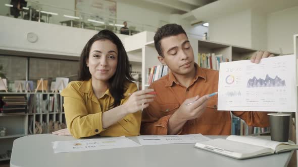 Two Colleagues s Talking By Business Corporate Video Call Showing Infographic Statistics, Mixed Race alt