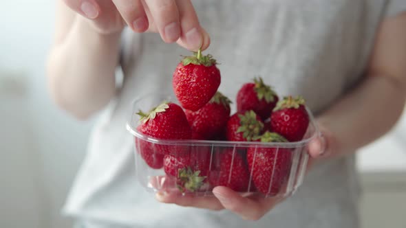Professional Farmer or Supermarket Customer Shows Plastic Box with Fresh Strawberries
