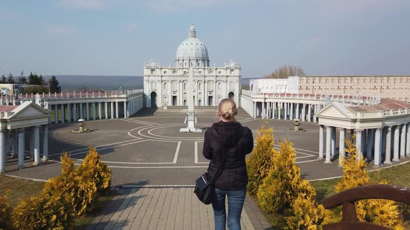 Female Makes Photo Walking on Foot Near a Miniature Model of the Saint Peter's Basilica, Vatican alt