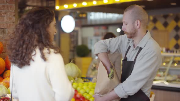Man Selling Fresh Produce to Female Customer in Food Market alt