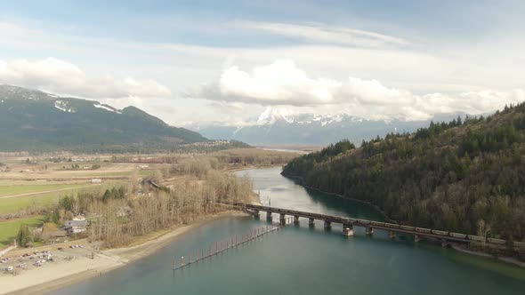 Aerial View of a River in the valley surrounded by Canadian Mountain Landscape. Green Farms. Harriso alt