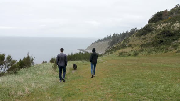 Couple walking towards the beach with their dog. alt