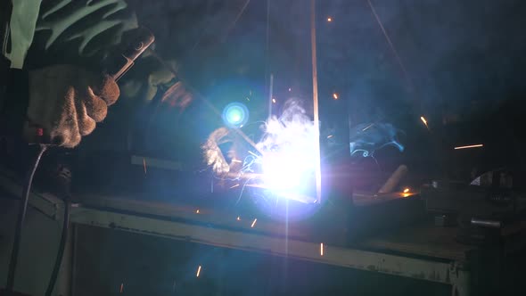Bright Light and Sparks From Welding. Industrial Worker in a Protective Mask Using a Modern Welding alt