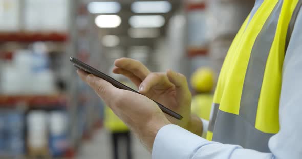 Close Up of Warehouse Worker Using Mobile Phone at Workplace alt