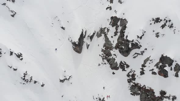 Aerial View. A Group of Skiers and Snowboarders, High in the Mountains, Prepare for a Steep Descent alt
