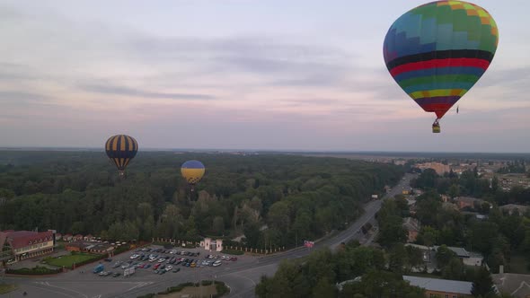 Colorful Hot Air Balloons Flying Over Green Park in Small European City at Summer Sunrise, Aerial alt