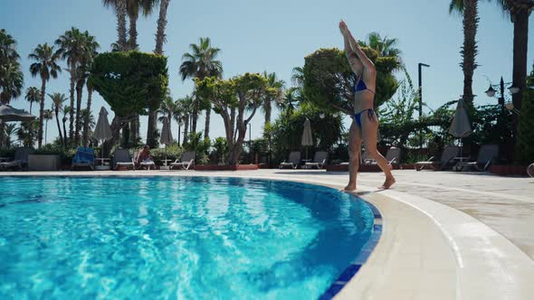 An Active Young Woman in a Swimsuit Dives Into the Pool and Splashes Glassy Water alt