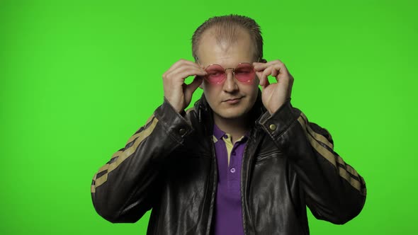 Cool Rocker Man in Brown Denim Jacket Puts on Pink Sunglasses, Looks at Camera and Claps His Hands alt