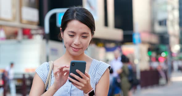 Woman checking on cellphone in the street alt