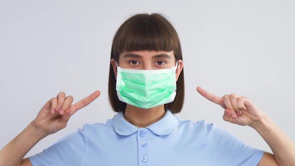 Young Woman Wear Protection Mask for Face and Pointing on It with Thumbs Up alt