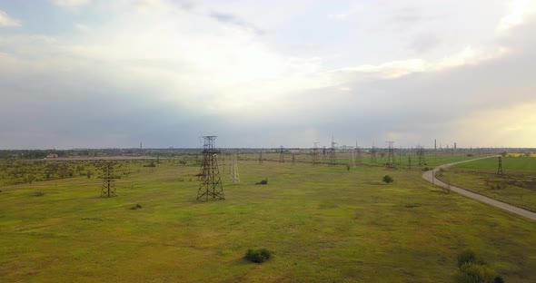 Large Pylons Of Power Lines On A Green Field, Next To The Road