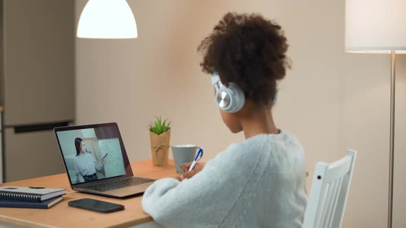 Young African Girl Sits at a Desk and Study Online Using a Laptop a Schoolgirl Learns in a Remote alt