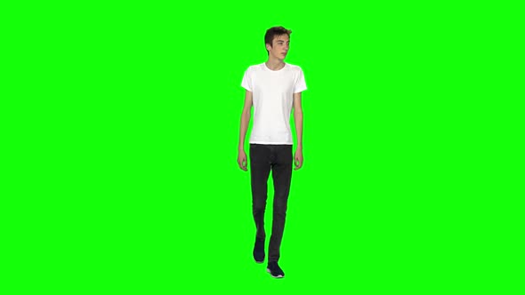 Tall Skinny Teen Guy Calmly Walking on Green Screen Background. Chroma Key. Front View. Slow Motion alt