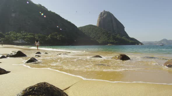 Slow motion shot of a woman walking along Red Beach in Rio. alt