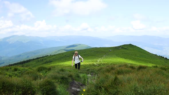 Happy Woman Hiker with Backpack Walks in Mountains at Sun Day