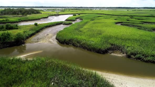 An aerial flyover of a stream creek river leading through a marsh to the Matanzas River in St. Augus alt