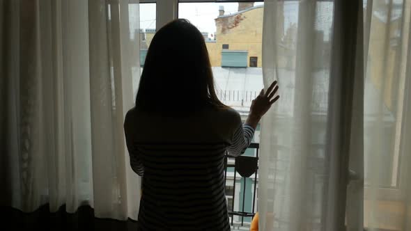 Young Woman Opening Curtains On Window At Morning And Go Out To Balcony.