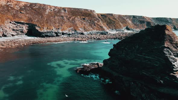 Rocks off the ocean coast line with turquoise water and dramatic cliffs Aerial view.